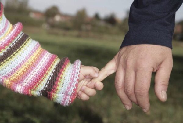 Young child holding the finger of a parent