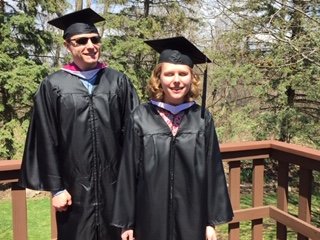 Visually impaired brother and sister standing outside in black graduation caps and gowns