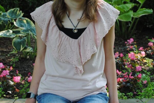 Visually impaired teenager sitting on a stone wall in front of plants