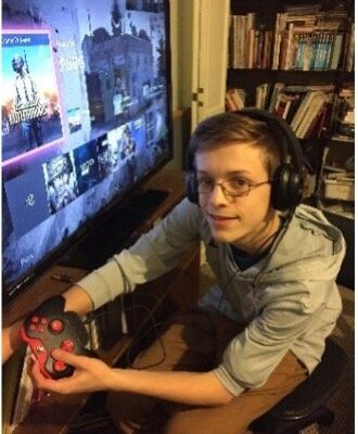 Teenage boy with glasses playing a video game on a large screen