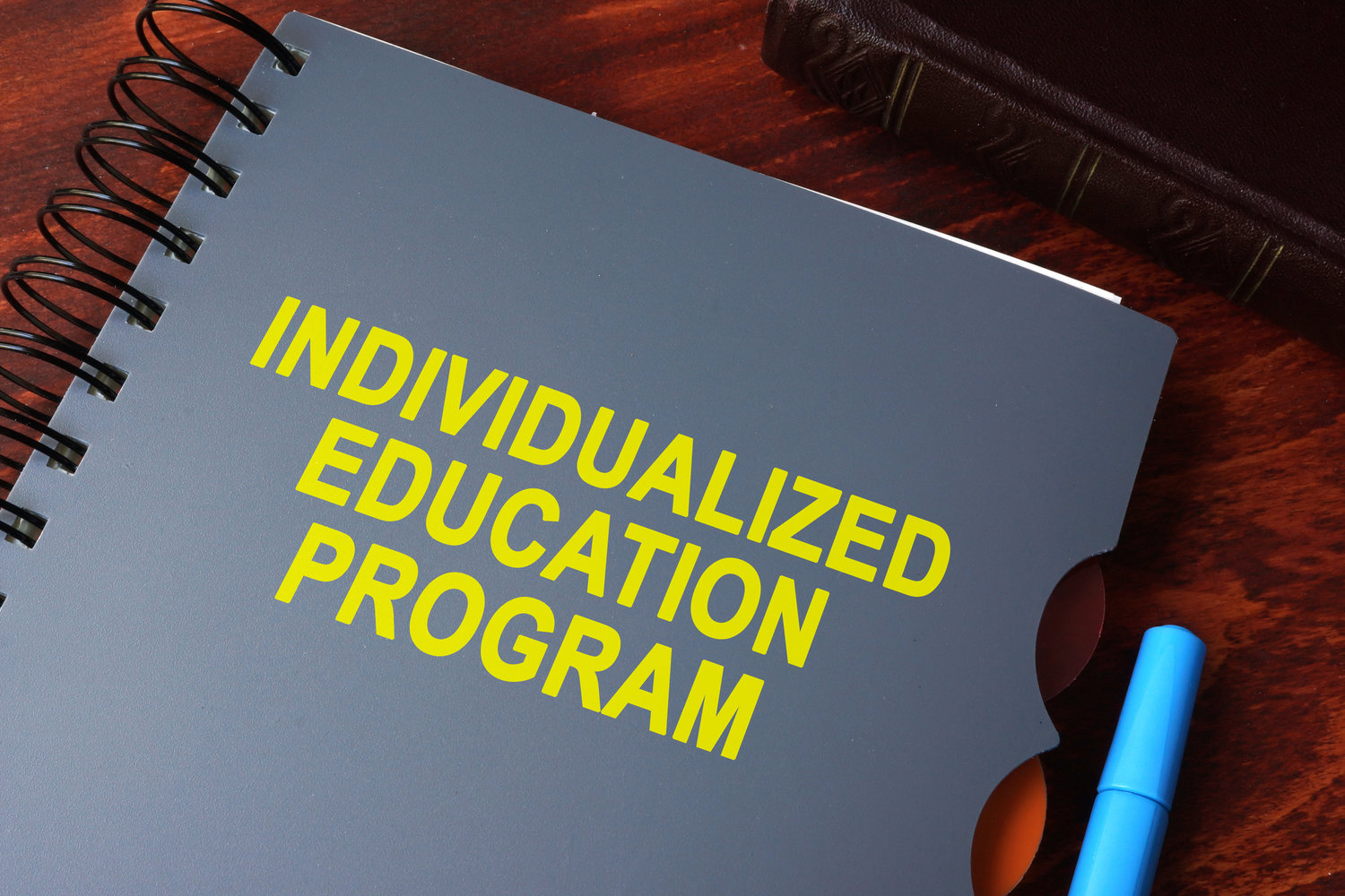 Grey notebook with the wordBook with title individualized education program (IEP) on a table.