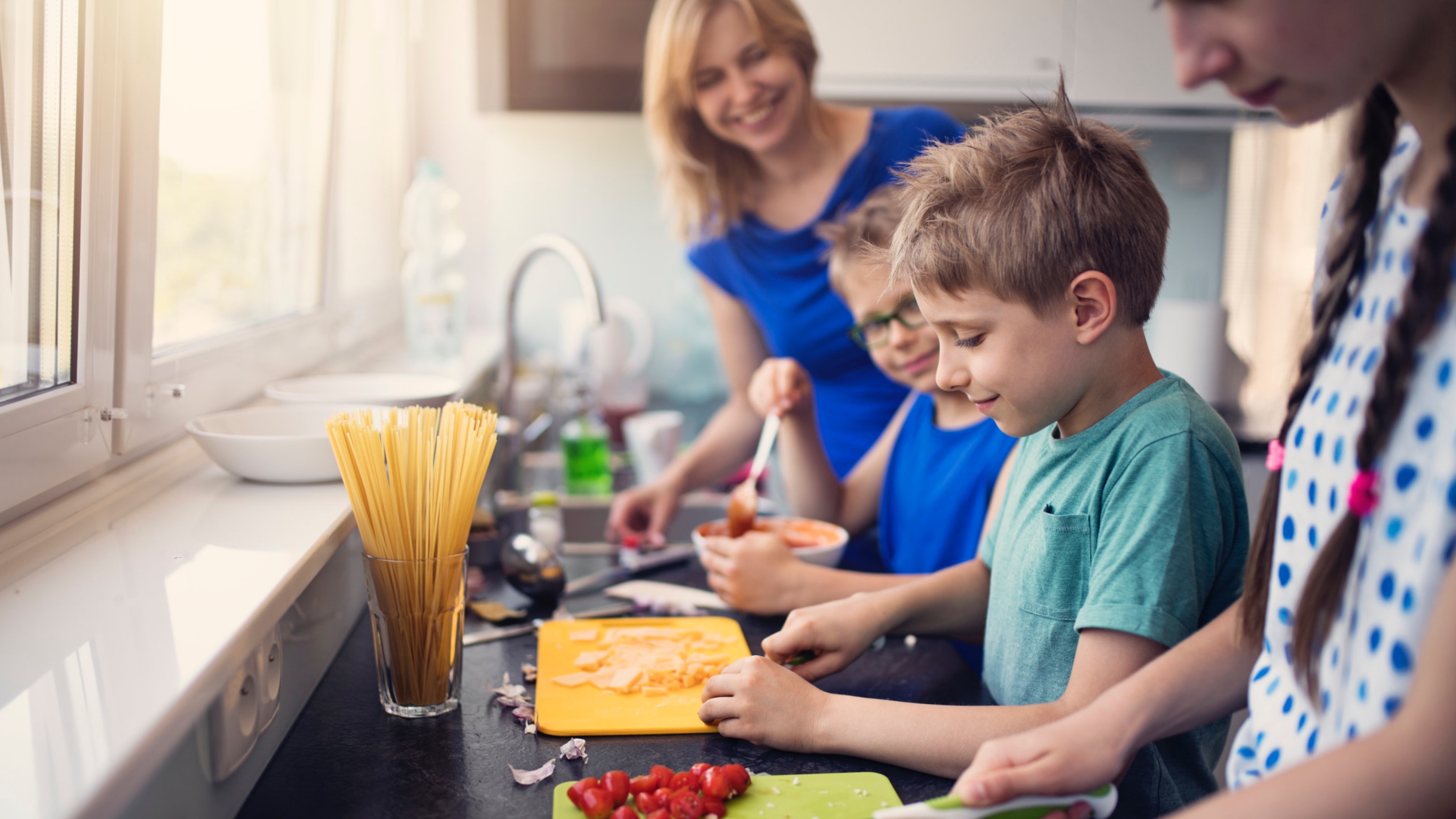 Mom and three kids at the kitchen counter preparing a meal