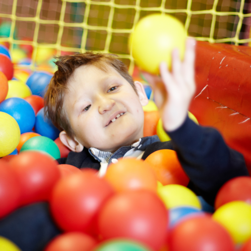 Young visually impaired boy in a colorful ball pit