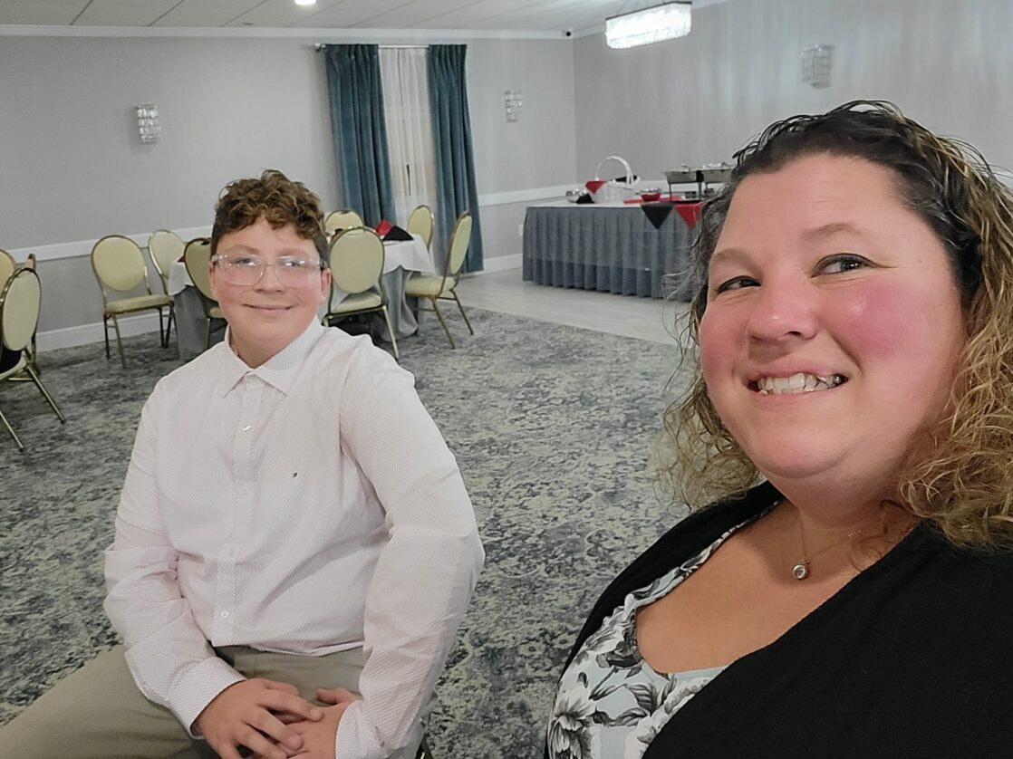 A smiling mother and son sitting in a hotel conference room