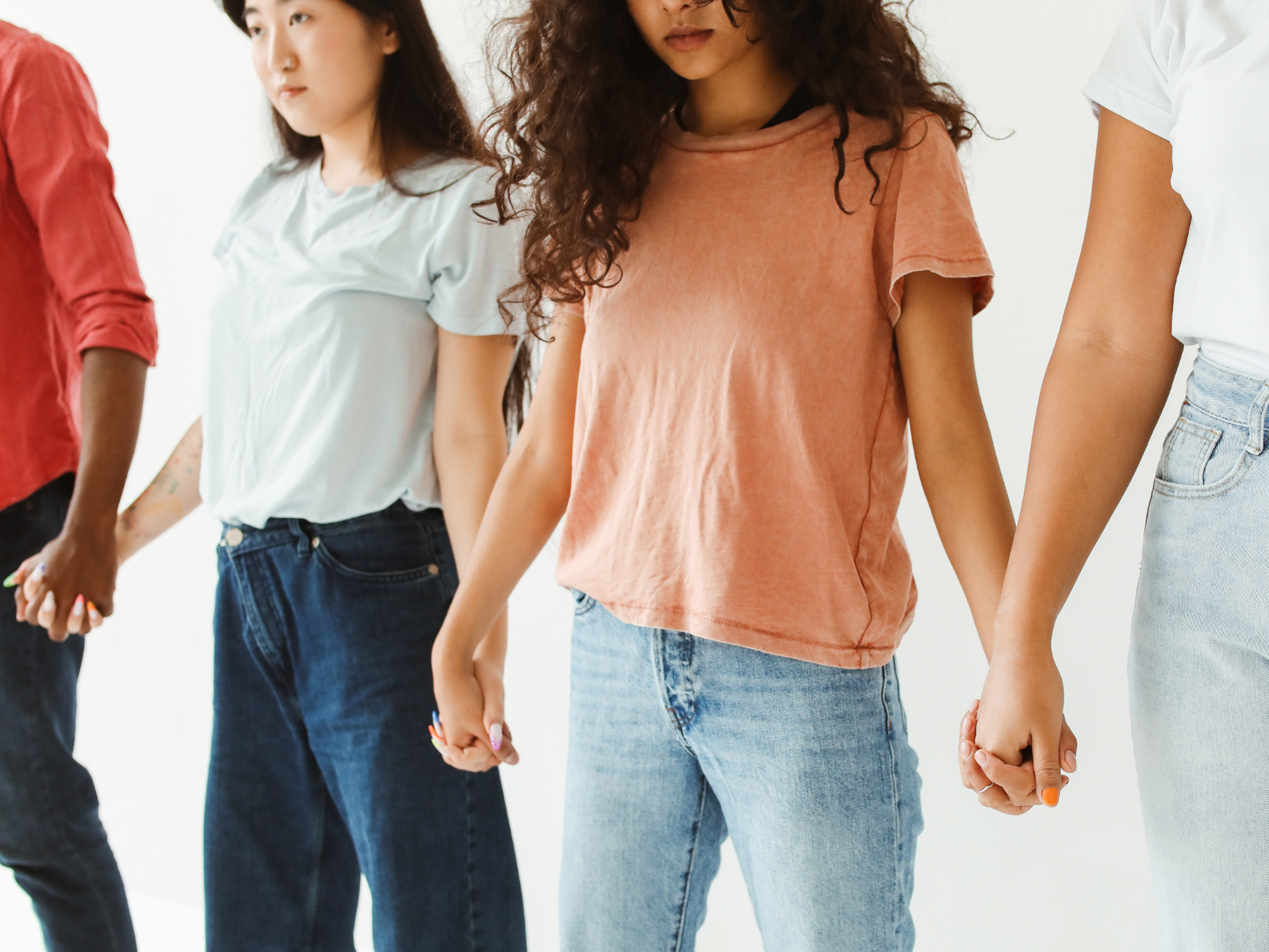 Four people standing in a straight line holding hands symbolizing solidarity