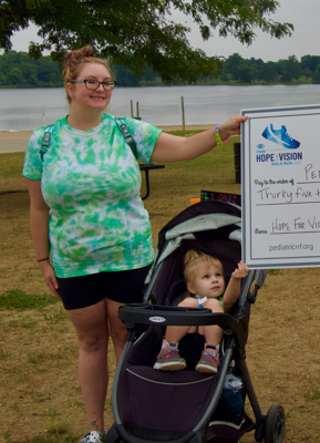 Smiling mother and child in a stroller holding an oversized check