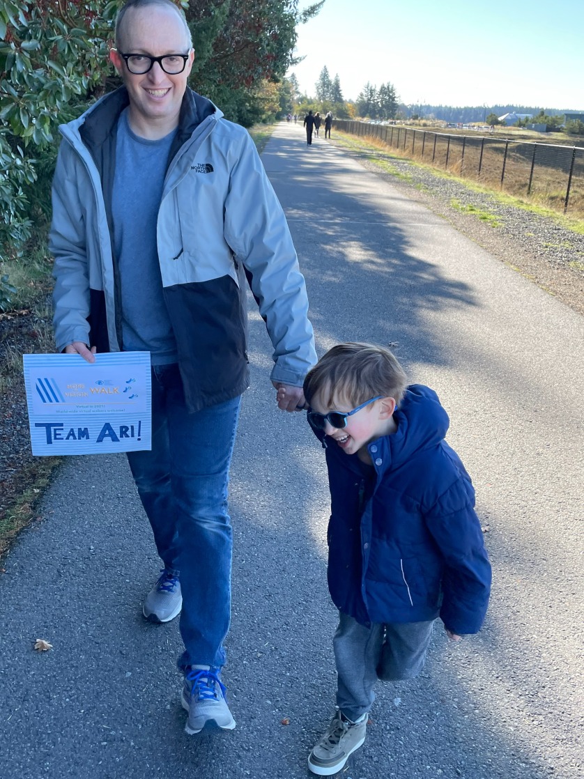Father and visually impaired young son walking down the sidewalk smiling and holding hands