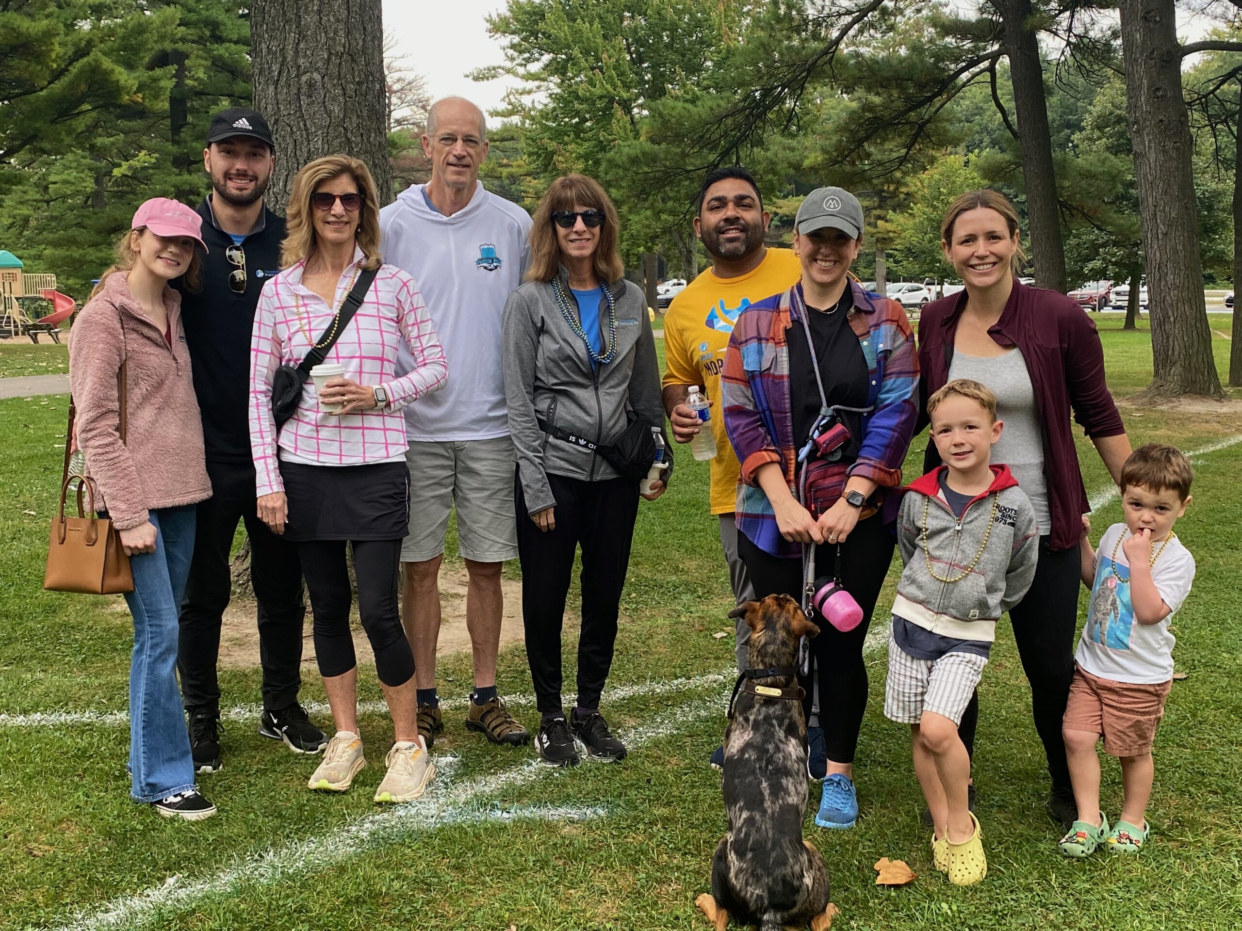 Multi-generational group of people smiling and standing in a park