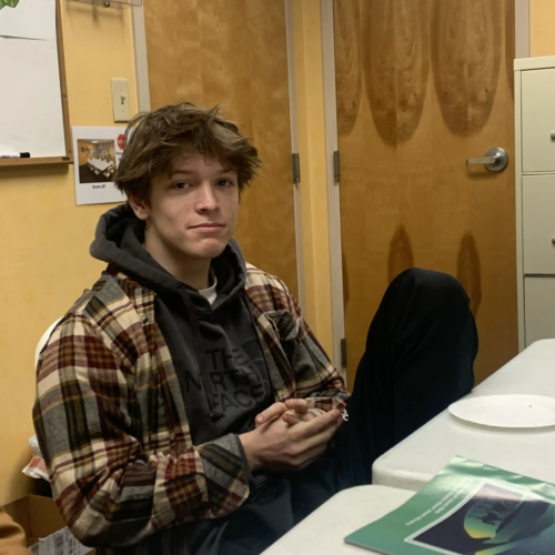 Teenage boy sitting at a table and looking at the camera