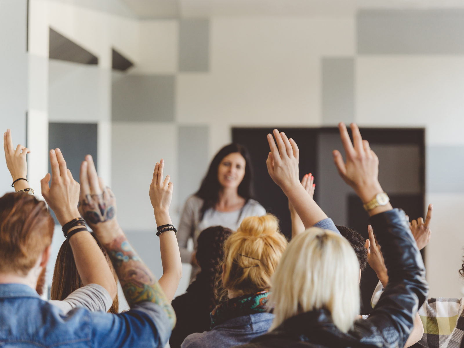 Woman in front of a group of people with their hands raised signifying self advocacy