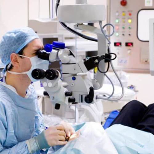 Surgeon looking through microscope at patient in operating room