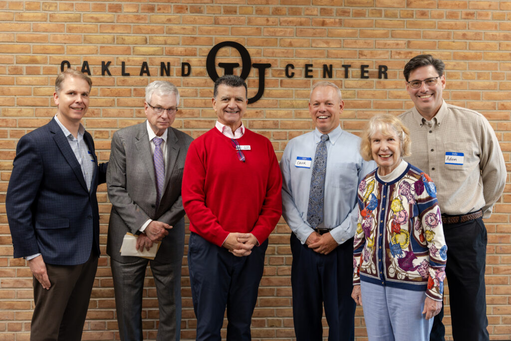 PRRF Board Members stand in front of a brick wall at Oakland University.