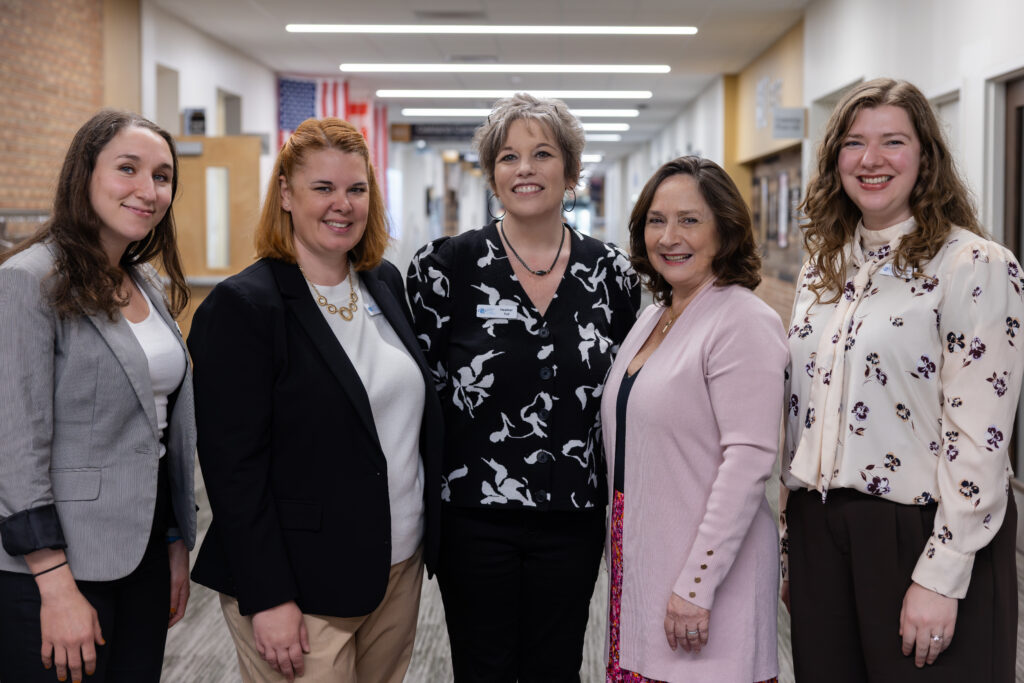 Four members of the PRRF staff stand posing in the hallway at Oakland University. They are dressed professionally.